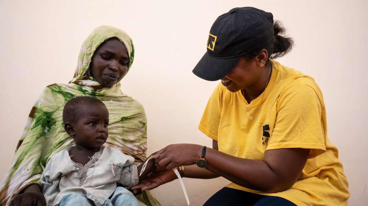 IRC person aiding small child and mother. Image Source: International Rescue Committee website